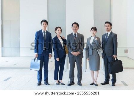 full length portrait of group of asian business people smiling together in office hall