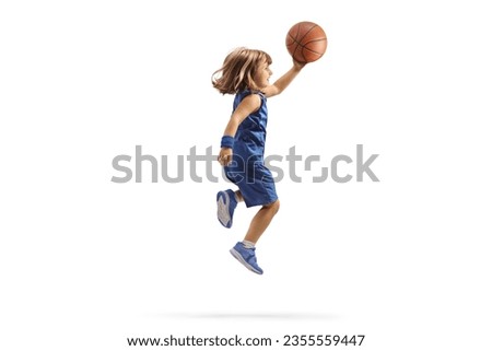 Girl in a blue sports jersey holding a basketball and jumping isolated on white background