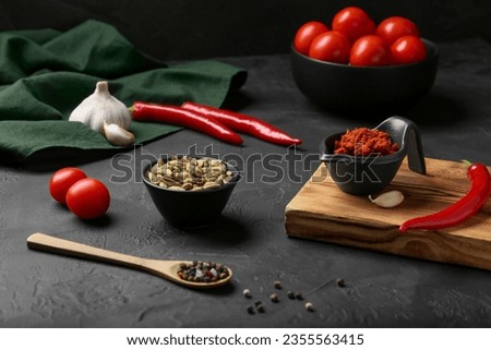 Dish with red curry paste and ingredients on black table Royalty-Free Stock Photo #2355563415