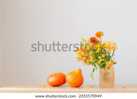 autumn bouquet and orange pumpkins  on wooden shelf on background gray wall