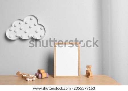 Empty square frame and different toys on wooden table indoors