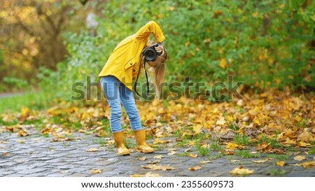 Happy photographer girl, little child, kid taking a picture with professional camera in nature