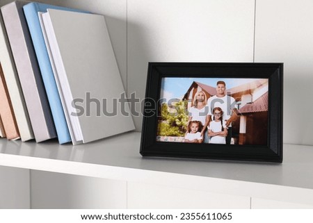 Frame with family photo and books on shelf indoors