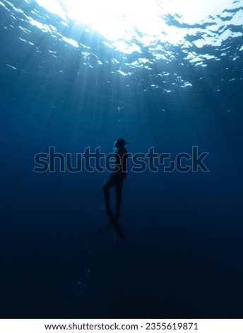 Freediver Swimming in Deep Sea With Sunrays. Young Man DIver Eploring Sea Life. Royalty-Free Stock Photo #2355619871