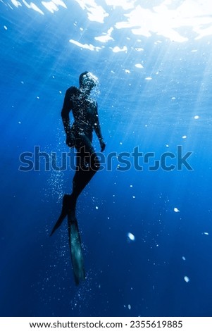 Freediver Swimming in Deep Sea With Sunrays. Young Man DIver Eploring Sea Life. Royalty-Free Stock Photo #2355619885
