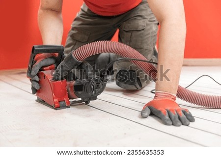 Construction worker cuts concrete floor for electrical cable, builder uses circular saw with diamond crown. Install underfloor heating. Royalty-Free Stock Photo #2355635353
