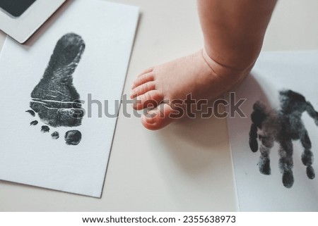 Baby footprints on white paper. Black footprint. The process of creating a baby footprint. Royalty-Free Stock Photo #2355638973