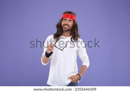 Stylish hippie man with sunglasses on violet background
