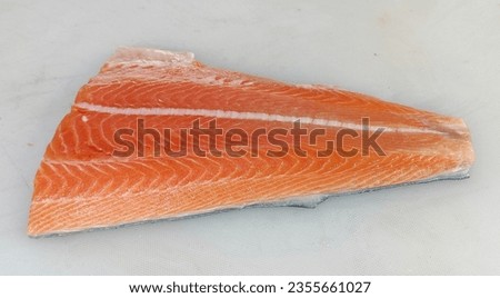 fresh raw cold seafood orange color Norwegian salmon whole fish ikan head, fillet, meat, cut, tail on white ice background halal food cuisine hyper market menu for restaurant ingredient design