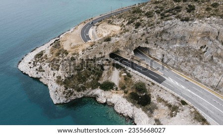 Aerial view photo of Athens' seaside highway road going through tunnel in rocks known as hole of Karamanlis. Attica, Greece, Europe