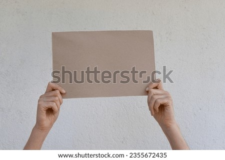 Blank cardboard poster held by a woman's hands