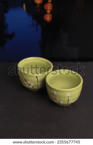 Cups with rice wine or tea on a dark background. Mid-autumn festival. River in China, lanterns full moon at night