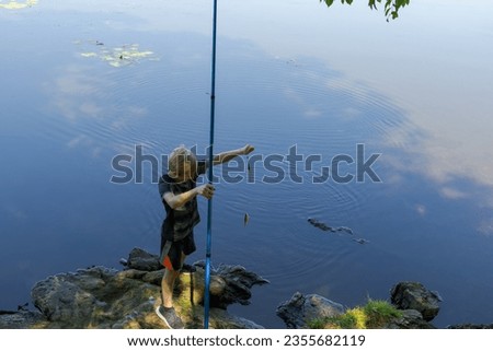 An overhead view of a teenager standing by a river fishing with a fishing rod. Sport fishing on the river in summer.