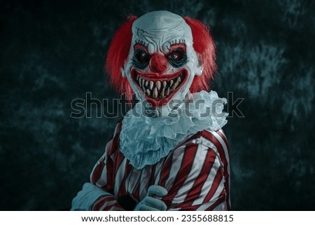 closeup of a mad evil redhead clown, wearing a white and red striped costume with a white ruff, with crossed arms and staring at the observer with a creepy smile, on a dark background
