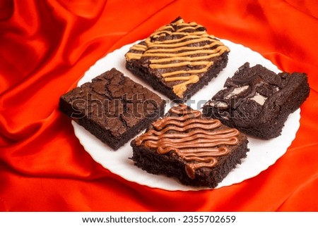 Four different flavour brownie in the white plate on the red background                              