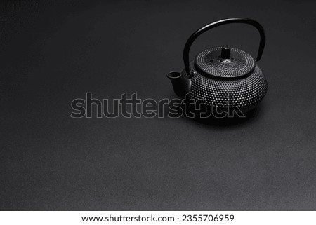 Black asian cast iron kettle on dark background with copy space