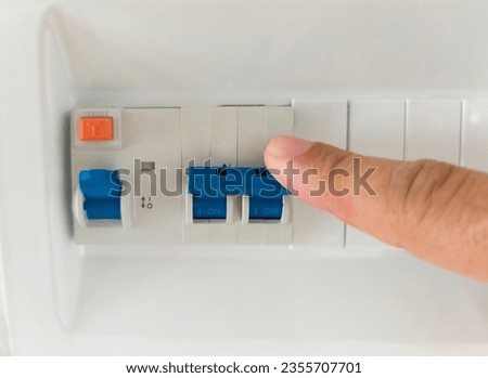 Finger pressing the lever of residual current operated circuit breaker. Selective focus Royalty-Free Stock Photo #2355707701