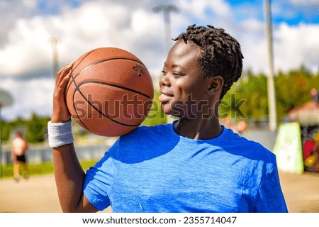 A Portrait of american basketball player guy standing at basketball court with ball