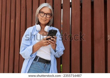 a well-groomed middle-aged woman with a bob haircut listens to music on a walk Royalty-Free Stock Photo #2355716487
