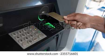 female hand applies a bank card to an ATM