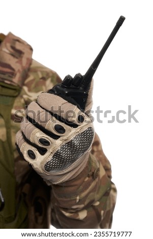 Unrecognizable man in camouflage uniform holding military walkie-talkie indoor. Close up view of portable radio sets, held by military soldier, isolated on white studio background. Connection concept.