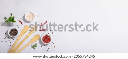 Culinary background with wooden kitchen utensil, spices and herbs. Set for preparation healthy food, flat lay. Hard light, dark shadow, light stone concrete background, banner format Royalty-Free Stock Photo #2355734245