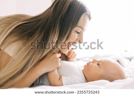 Authentic shot of young neo mother is playing with her newborn baby in a nursery in a morning. Concept of children,baby, parenthood, childhood, life, maternity, motherhood