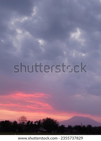 view of rice fields and mountains at sunset with dark cloudy sky