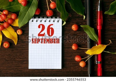 calendar date on wooden dark desktop background with autumn leaves and small apples. September 26 is the twenty-sixth day of the month.