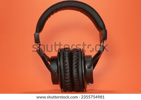 Black stereo studio monitor headphones for listening music, mixing, recording, mastering on orange background isolated