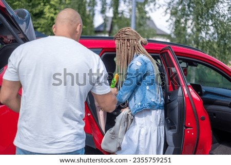 A woman and a man take things from a red car and get ready for a trip. Copy space. High quality photo