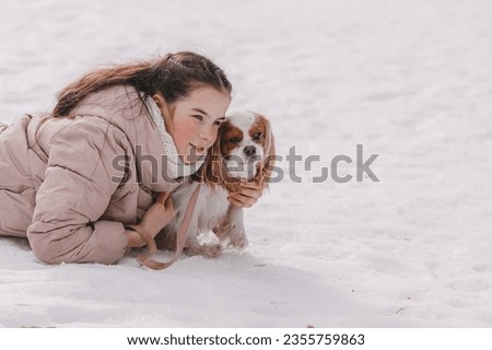 Cute girl playing with dog in the snow. The concept of Christmas and New Year