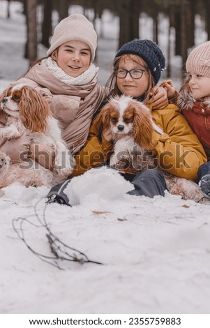 Three adorable young girls having fun together by beautiful frozen park, forest. Cute sisters playing in a snow with a dog. The concept of Christmas and New Year