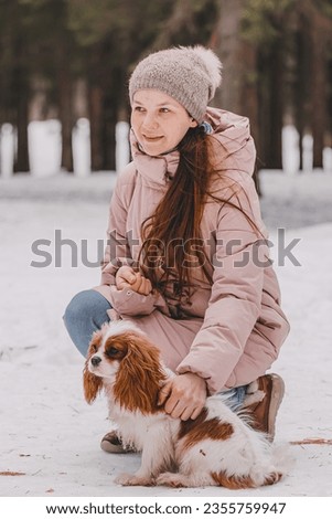Cute woman playing with dog on the winter park, forest. The concept of Christmas and New Year