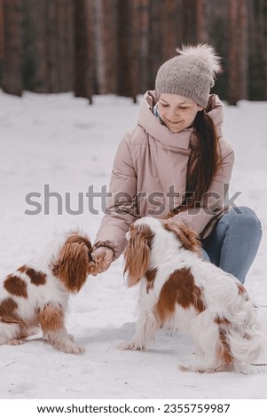 Cute woman playing with dogs on the winter park, forest. The concept of Christmas and New Year