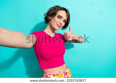 Photo of cheerful lovely girl make selfie hand finger demonstrate thumb up isolated on teal color background