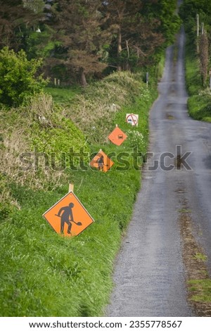 rural irish road with several street signs in a row - for example construction site sign and sign for no overtaking