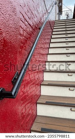 Red brick will with wooden steps and black iron railing. Vertical format photograph of the stair case. 