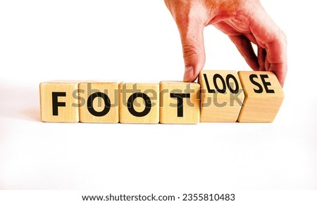 Foot or footloose symbol. Businessman turns wooden cubes and changes word Foot bad to Footloose. Beautiful white table white background. Business foot or footloose concept. Copy space.