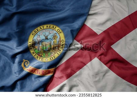 big waving colorful national flag of alabama state and flag of idaho state . macro