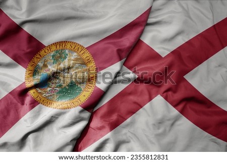 big waving colorful national flag of alabama state and flag of florida state . macro