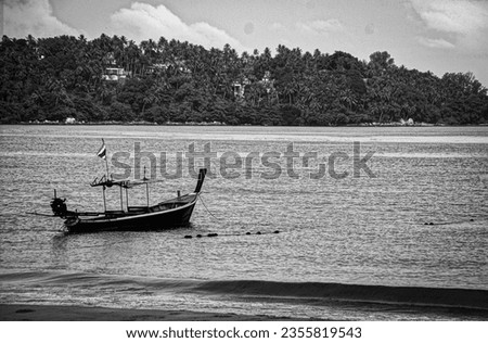 Black and white photo of a single wooden boat in Thailand next to a beach                               