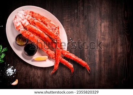 White plate with boiled claws of kamchatka crab, lemon and butter over light-blue stone background, studio shot Royalty-Free Stock Photo #2355820329