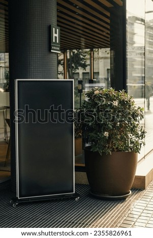 Vertical outdoors shot of a black blank board in front of a restaurant.