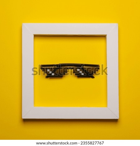 8 bit pixel sunglasse in white frame on yellow background. Creative layout. Minimalism