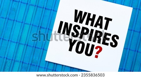 blank note pad with WHAT INSPIRES YOU text on blue wooden background