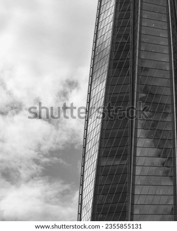 A curved glass skyscraper facade reflecting blue sky. Business center, corporation headquarters. Urban, modern architecture. Black and white photography