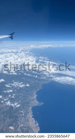 this is a picture of a plane heading Paris. we can see clouds, sea and a part of the country
