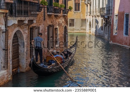 Venetian gondolier riding gondola through the green canals of venice italy Royalty-Free Stock Photo #2355889001