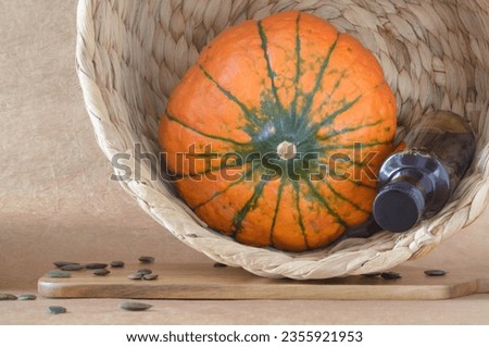 Still life with an orange round pumpkin, a bottle of pumpkin oil